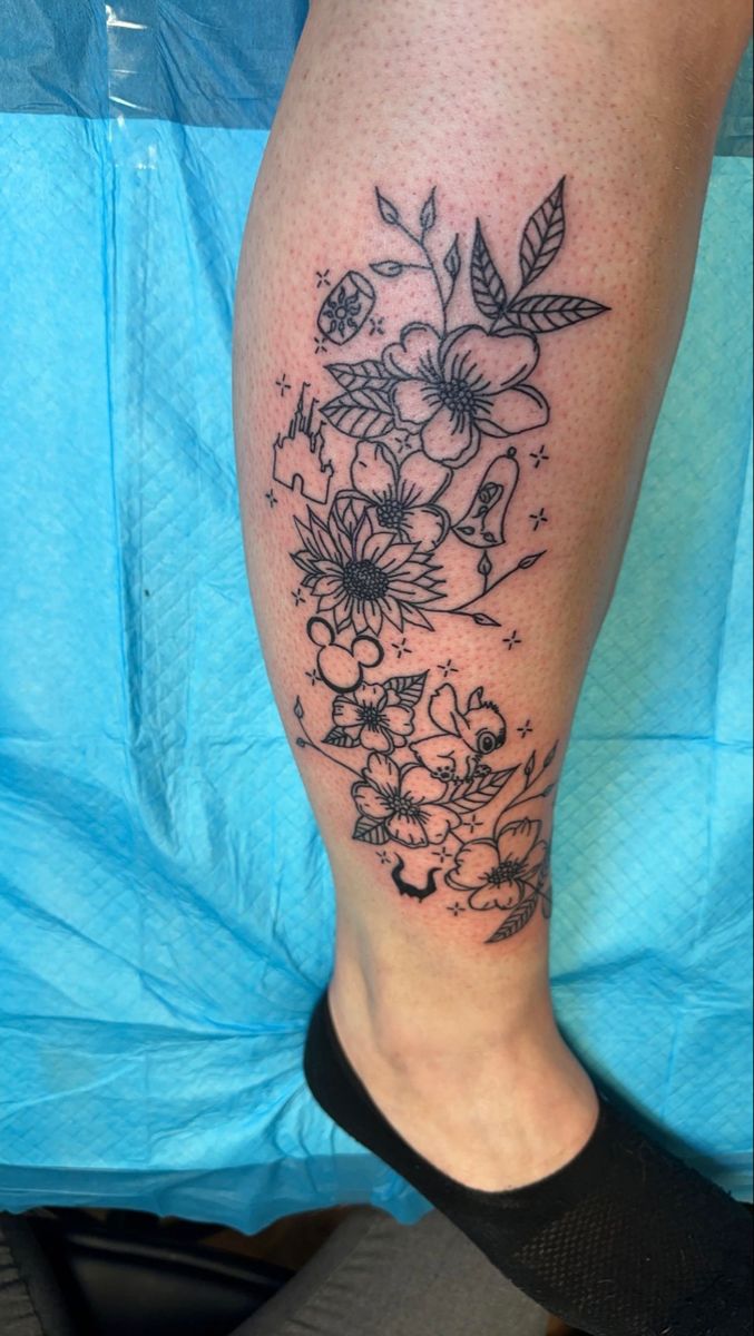 a woman's leg with flowers and leaves tattooed on her legs, in black ink