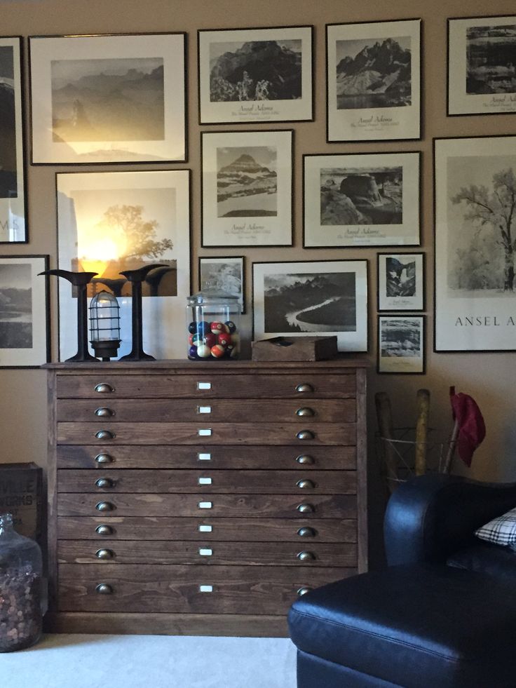 a living room filled with lots of pictures on the wall above a chest of drawers