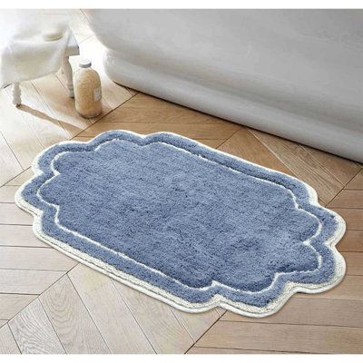 a bathroom rug with a blue border on the floor next to a white bath tub