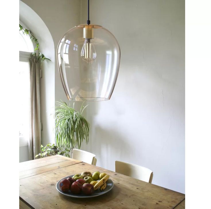 a bowl of fruit sitting on top of a wooden table next to a light fixture