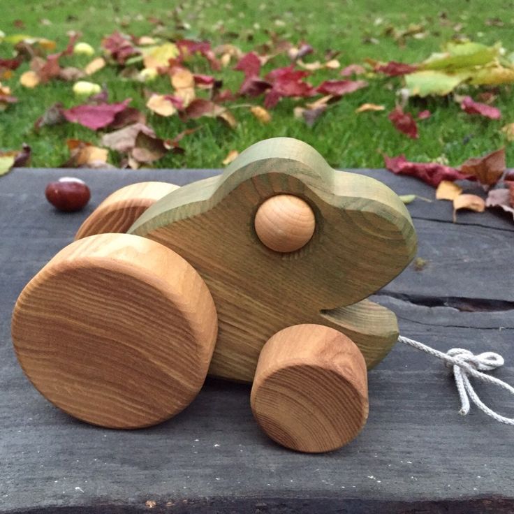 a wooden toy bear sitting on top of a piece of wood