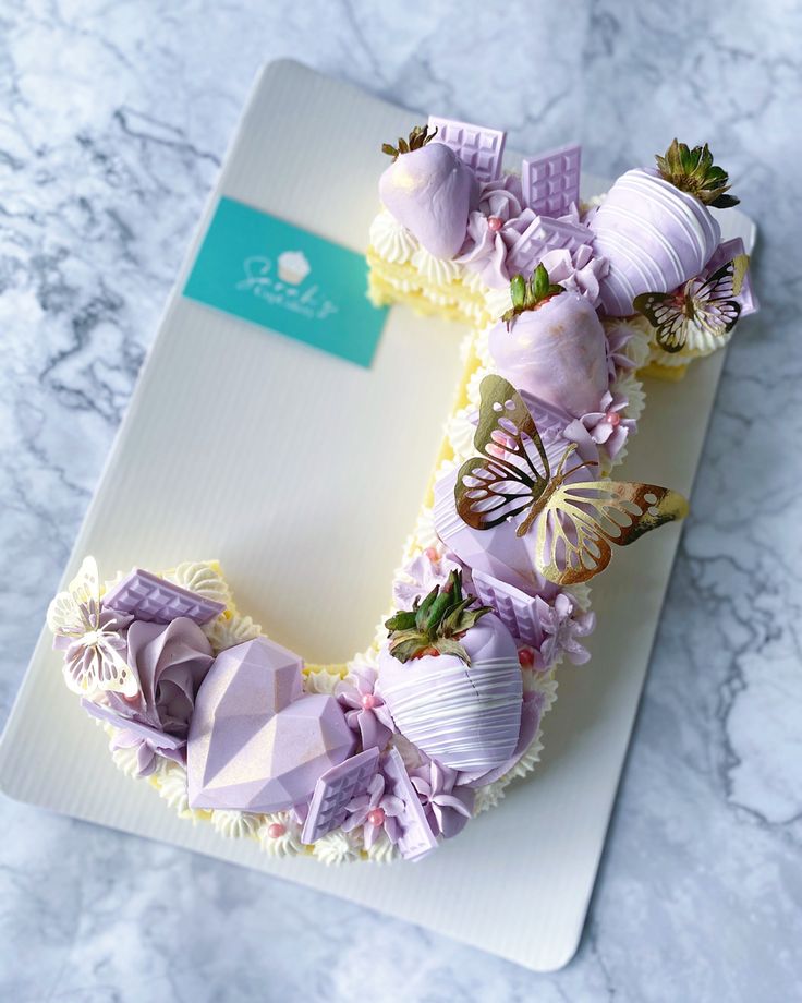 there is a cake decorated with purple flowers and butterflies on it's icing