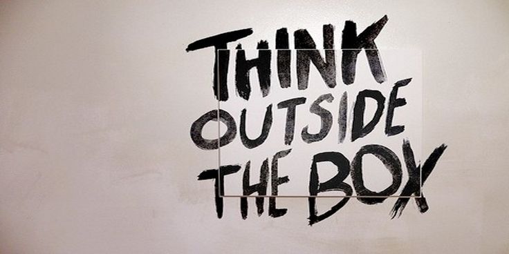 the words think outside the box are painted on a white wall with black spray paint