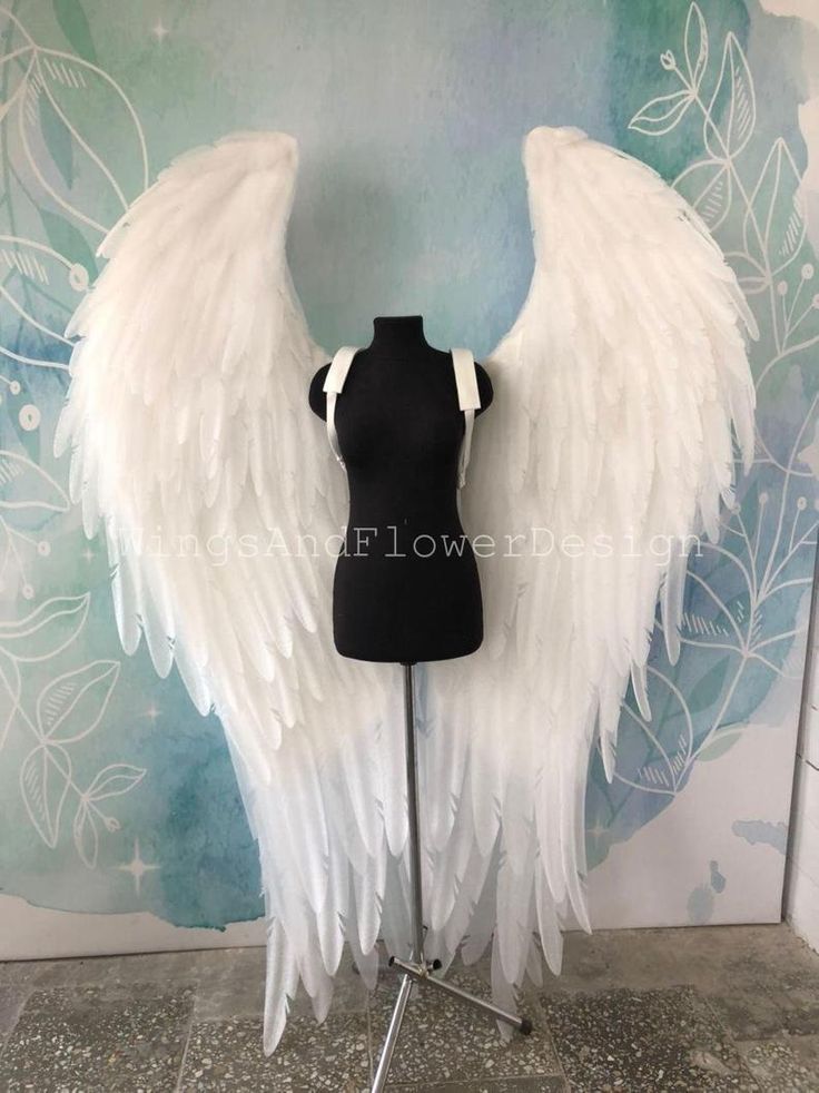 a mannequin with white angel wings on it's head and torso, standing in front of a wall