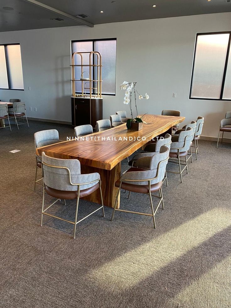 a large wooden table surrounded by chairs in an empty room with lots of windows on the wall