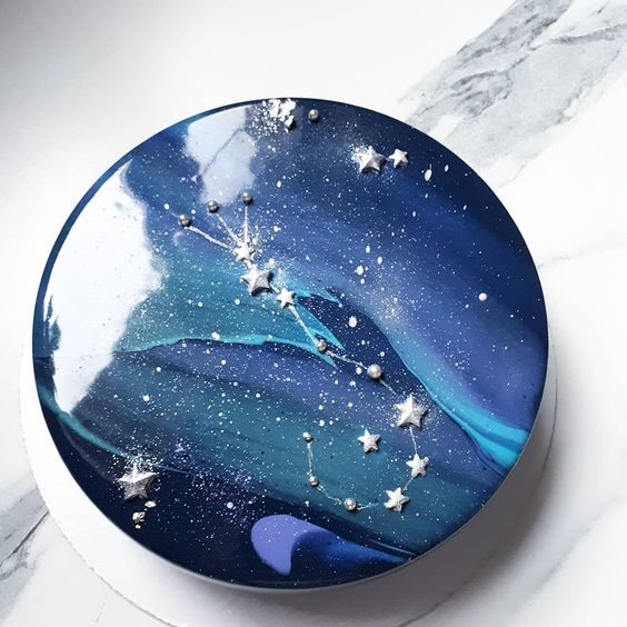 a blue and white cake with stars on it sitting on a marble counter top next to a clock