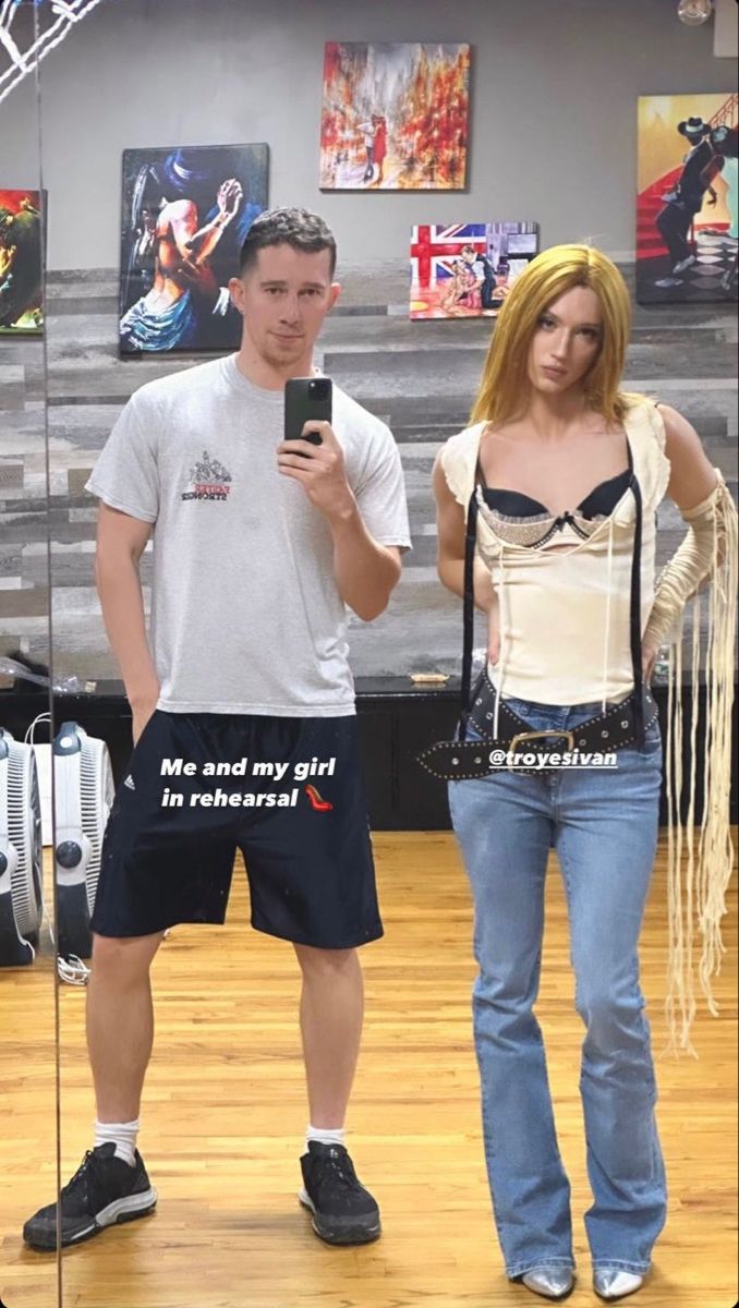 a man standing next to a woman holding a cell phone