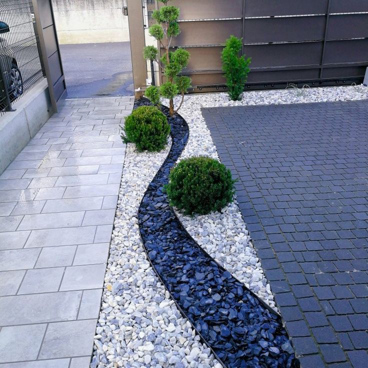 a garden with rocks and gravel in front of a house