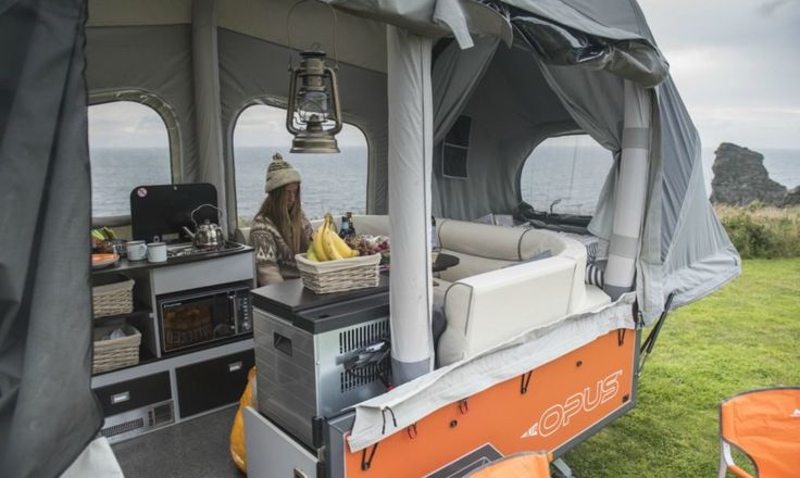 an orange and white tent with some food on the table in front of it next to water