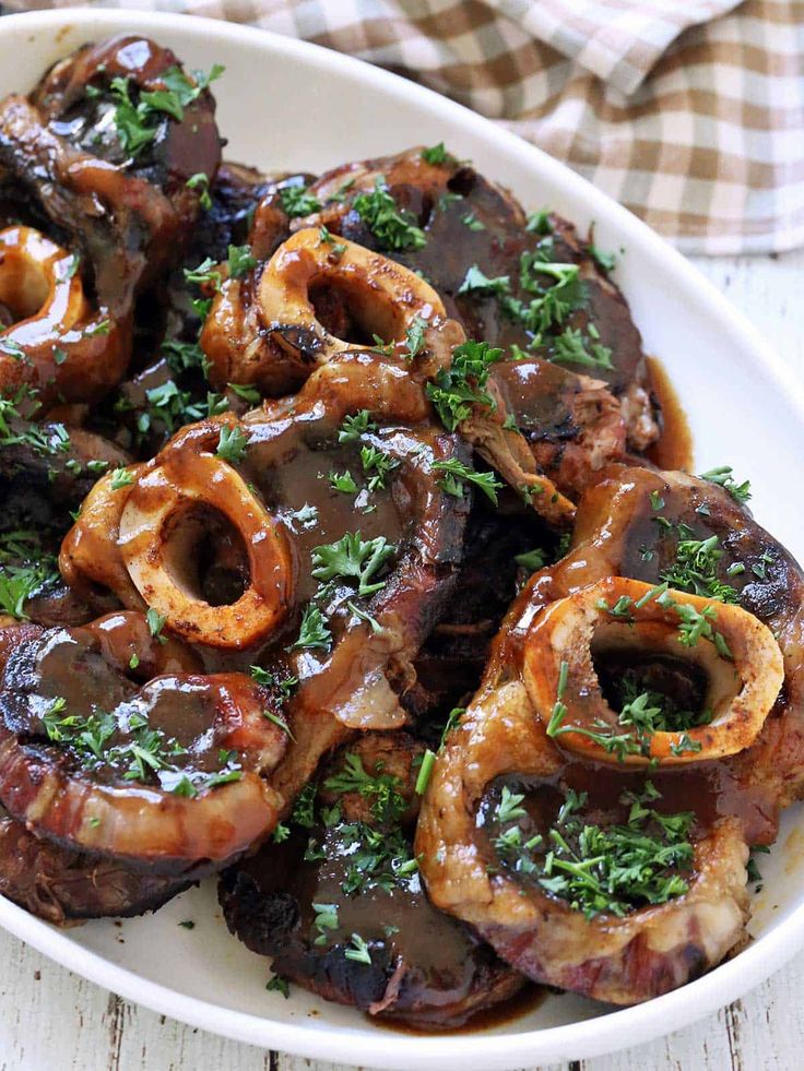 a white plate topped with onion rings covered in sauce and garnished with parsley