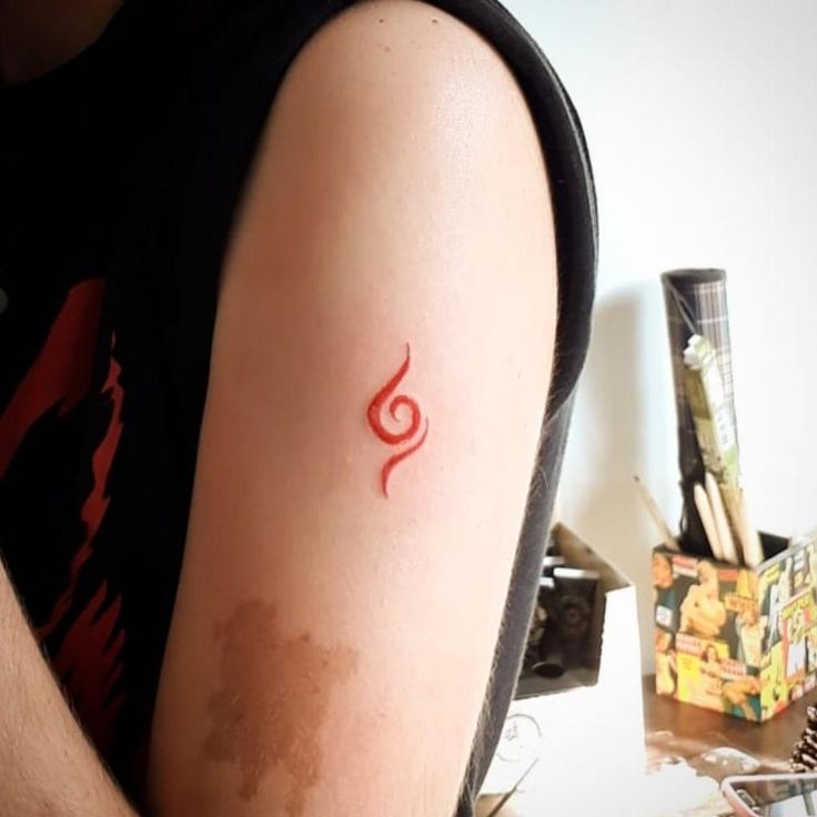 a person with a red tattoo on their arm sitting in front of a computer desk