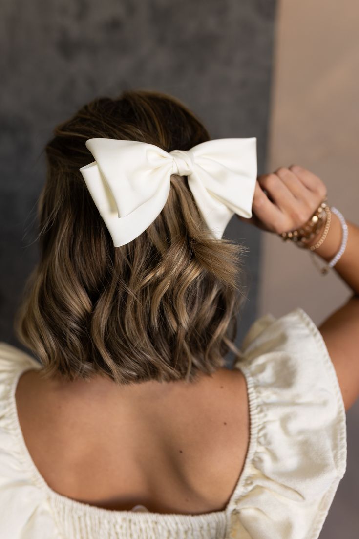 Back view of model's hair - model is wearing the Emmaline Ivory Satin Short Hair Bow that features ivory satin fabric, a two layered design, and a clasp closure. Short Bridal Hair Styling Tools, Small Satin Hair Bow, Hair Accessories For Women With Short Hair, Shoulder Length Hair Cocktail Party, Bridal Satin Hair Bow, Small Hair Bows Satin, Short Hair Guest Wedding, Hair Put Ups For Mid Length Hair, Short Bridal Hair Styling Accessories