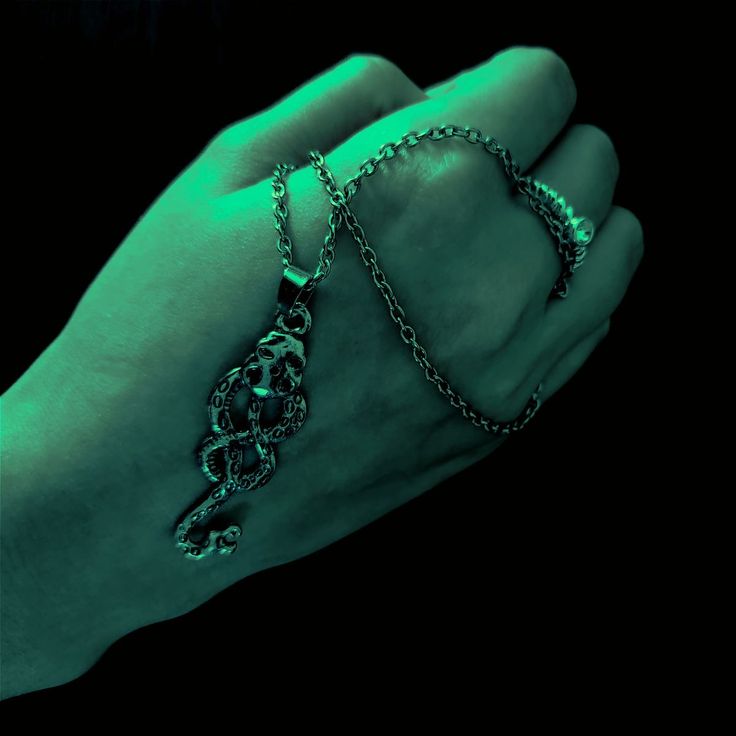 a hand with a chain on it that has a green glow in the dark behind it