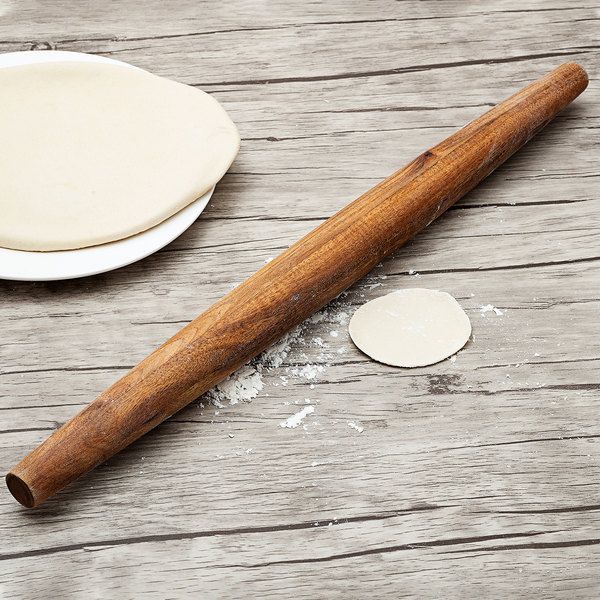 a wooden rolling pin sitting on top of a table next to a doughnut shell