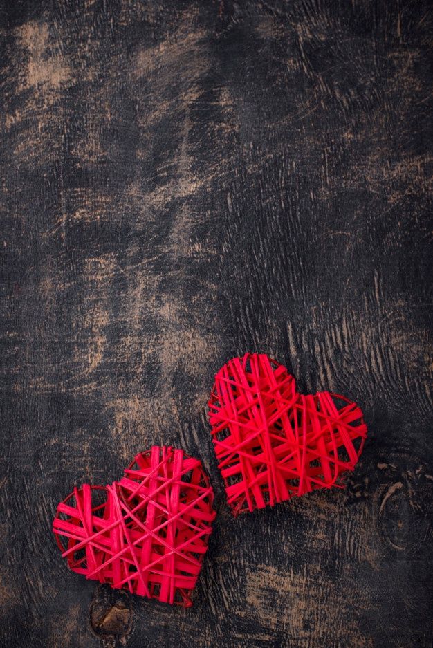 two red hearts made out of sticks on a black background with space for text or image