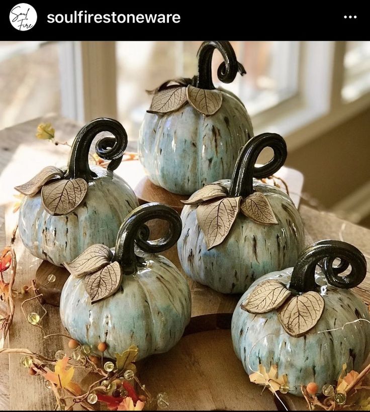 four decorative pumpkins sitting on top of a wooden table