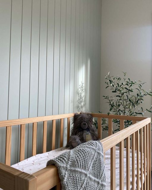 a teddy bear sitting on top of a wooden crib