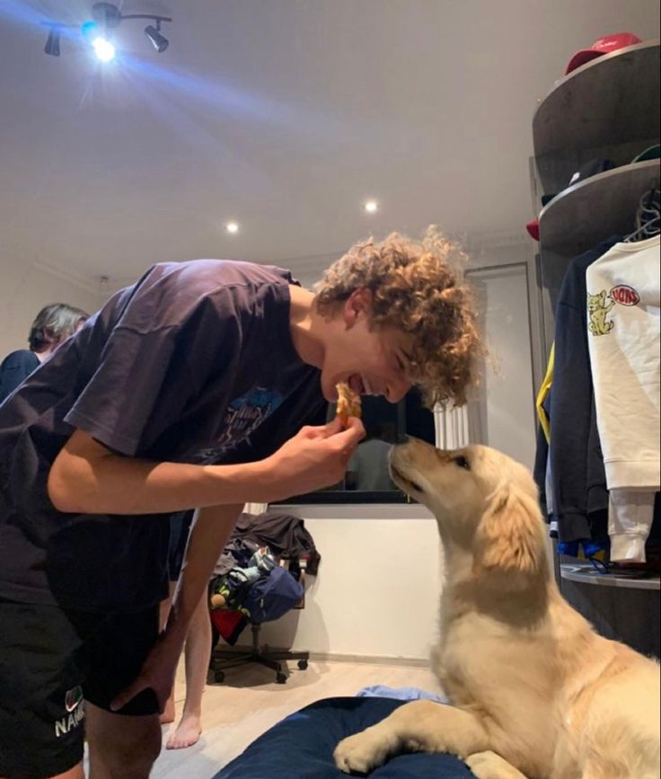 a young man is feeding his dog something