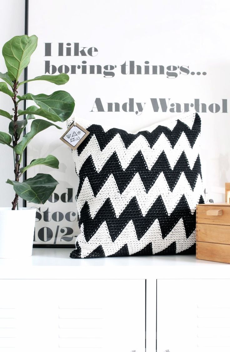 a black and white pillow sitting on top of a table next to a potted plant