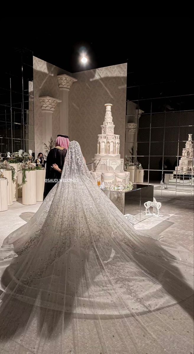 a bride and groom standing in front of a wedding dress on display at a museum