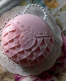 a pink object sitting on top of a flowery tablecloth covered bed spreader