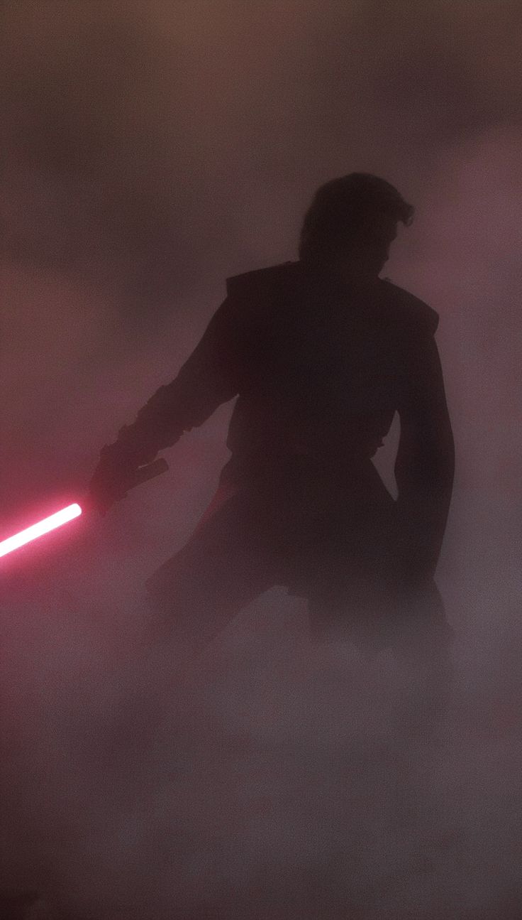 the silhouette of a person with a light saber in their hand and fog behind them