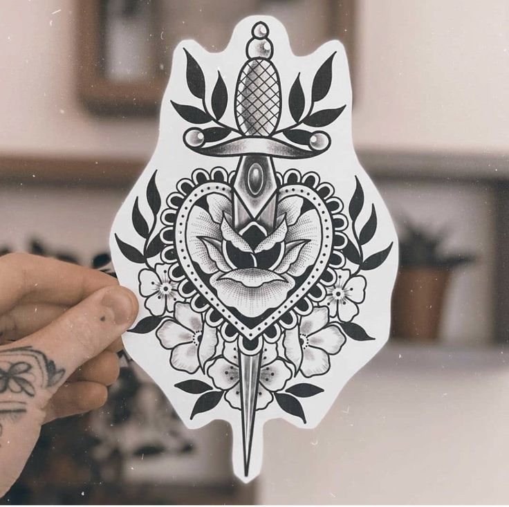 a person holding up a sticker with a tattoo design on it