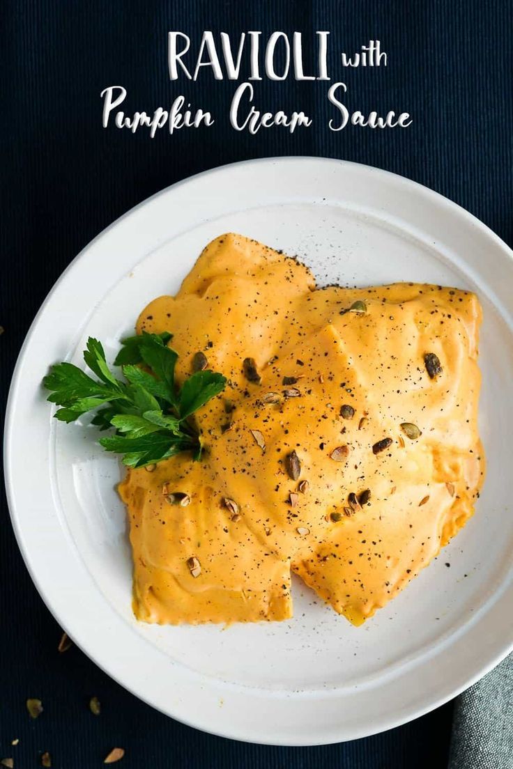 two pieces of ravioli with pumpkin cream sauce on a white plate, garnished with parsley