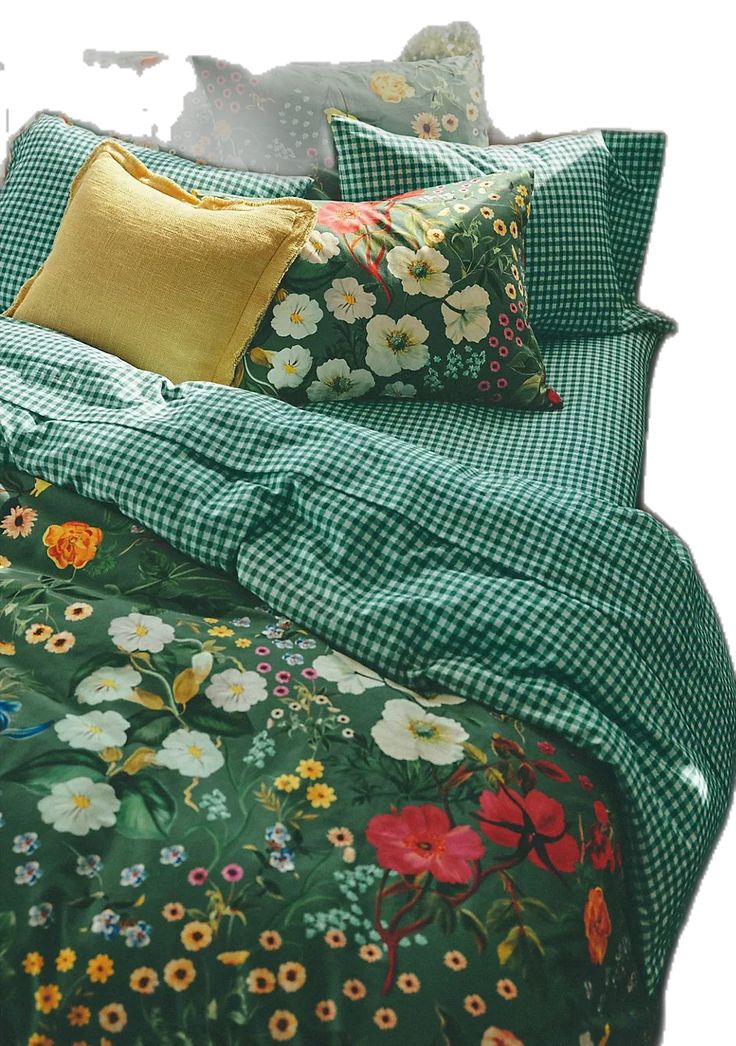 a bed covered in green and yellow floral comforter sets with pillows on top of it