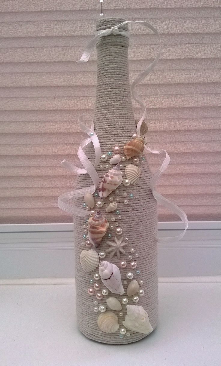 a bottle decorated with seashells and ribbons