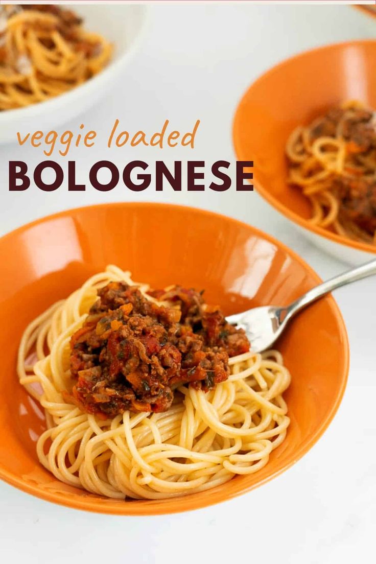 two orange bowls filled with spaghetti and meat on top of a white table next to the words, veggie loaded bologinee