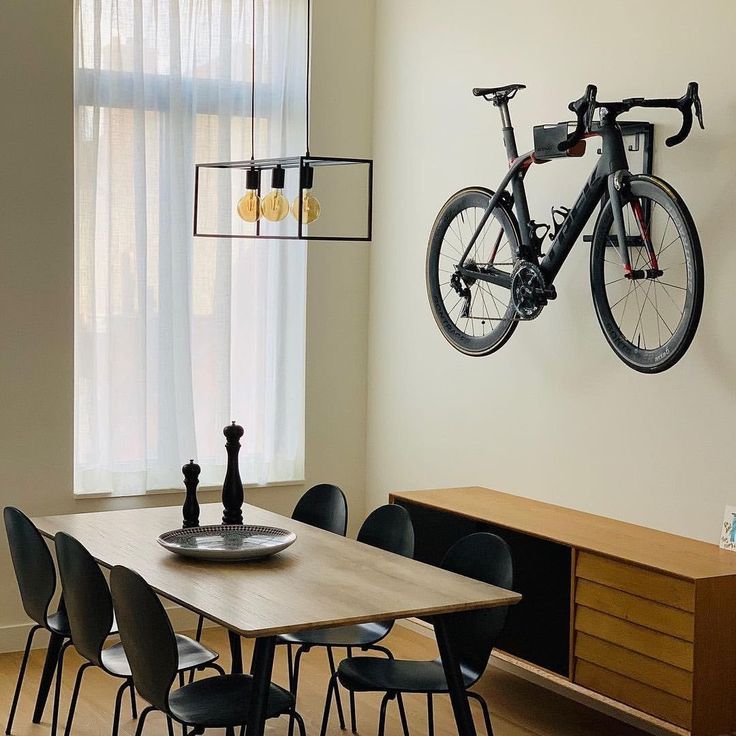 a dining room table with chairs and a bicycle mounted to the wall