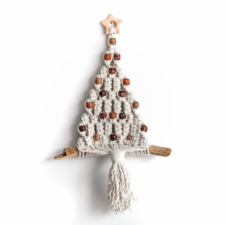 a crocheted christmas tree ornament hanging on a white wall with brown beads