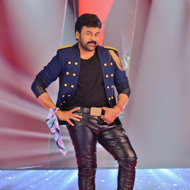 a man standing on top of a stage with his hands in his pockets while wearing leather pants