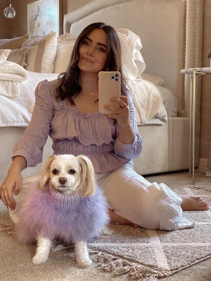 a woman sitting on the floor taking a selfie with her dog in front of her