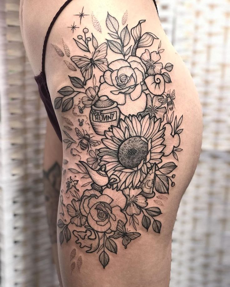 the back of a woman's thigh with flowers and leaves tattoo on her thighs