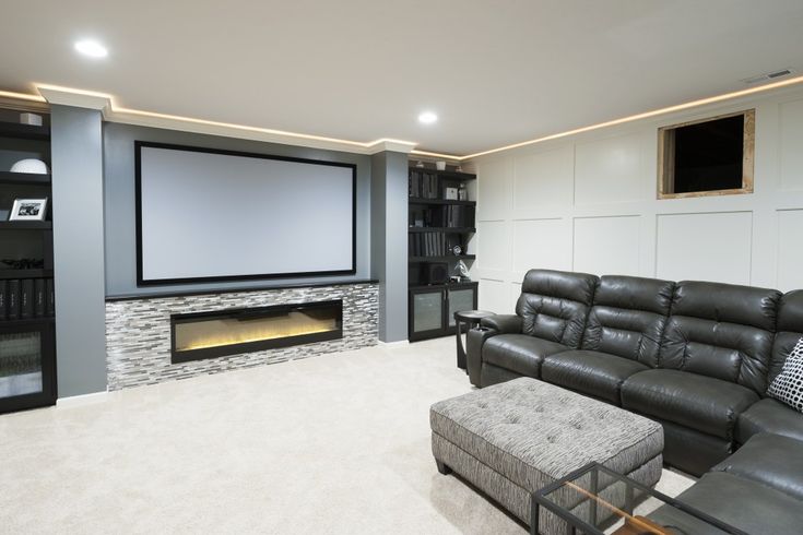 a living room with a large screen tv and couches in front of the fireplace