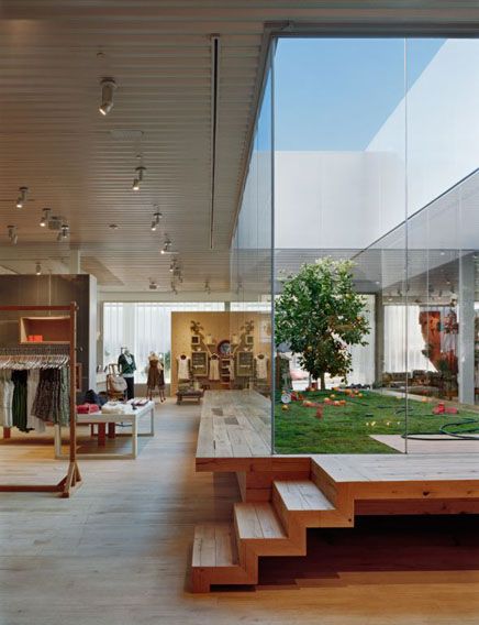 the inside of a store with glass walls and wooden steps leading up to an open area