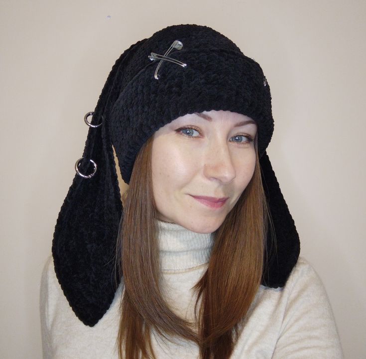 a woman wearing a knitted hat with buttons on the side and a cross at the top