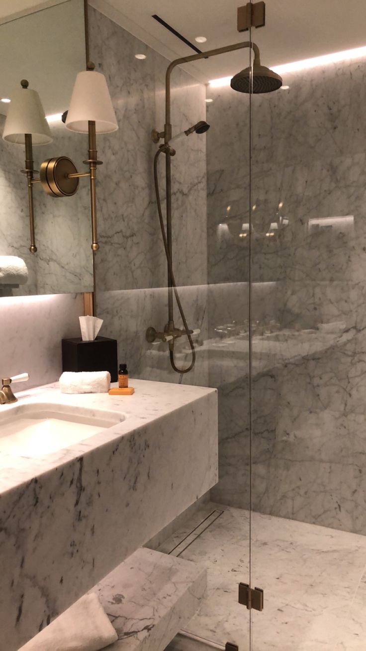 a bathroom with marble walls and flooring next to a walk - in shower stall