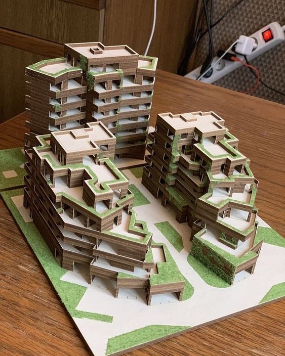 a paper model of some buildings sitting on top of a wooden table next to a computer mouse