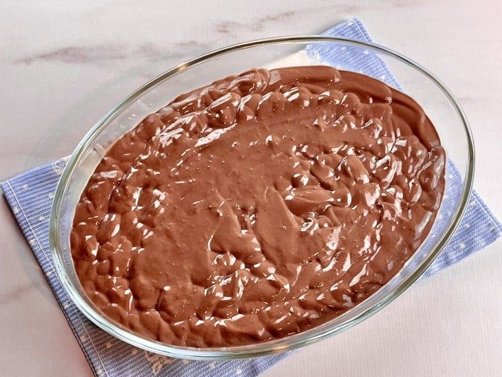 a glass bowl filled with chocolate frosting on top of a blue napkin