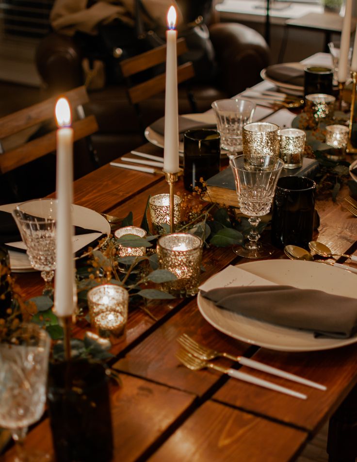 a wooden table topped with plates and candles