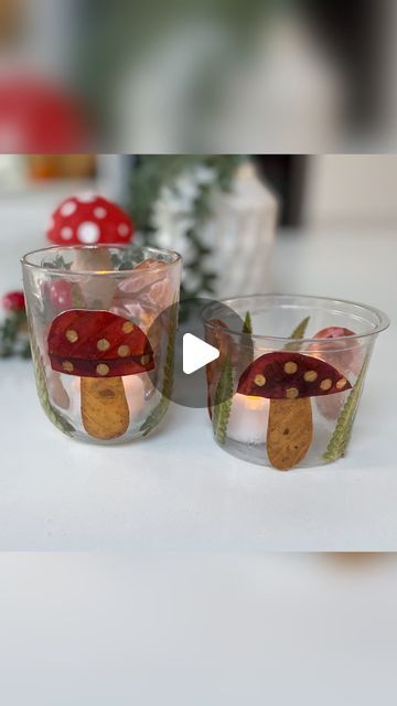 two glass cups with mushrooms in them sitting on a table next to plants and candles