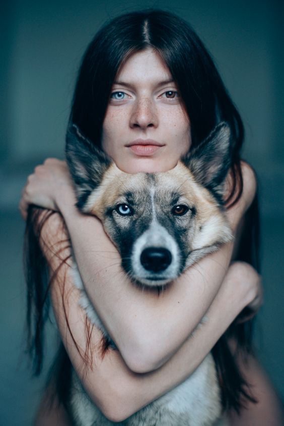 a woman holding a dog with her arms around her neck and looking at the camera