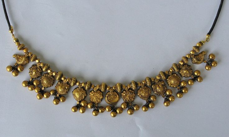 Golden Necklace from Kolhapur, India Gold, filled with wax to prevent denting Early 20th century Size of the golden part: 18cm Length of the full necklace 70 cm The necklace has 13 gold pendants, six of which appear in pairs. On each pendant are three small gold beads Between the pendants different gold beads The goldparts are filled with wax to prevent denting Mounted on a cord with a sliding knot so that it can be worn at different lengths Very decorative with a beautiful patina This is only a Traditional Engraved Temple Necklace For Rituals, Engraved Temple Necklace For Wedding, Gold Pendant Necklace With Antique Finish, Antique Temple Necklace With 17 Jewels As Gift, Engraved Brass Temple Jewelry Necklaces, Temple Necklace With 17 Jewels For Festivals, Traditional Temple Necklace With 17 Jewels For Puja, Gold Kundan Necklace With 17 Jewels For Ceremonial Use, Gold Engraved Necklaces For Festivals