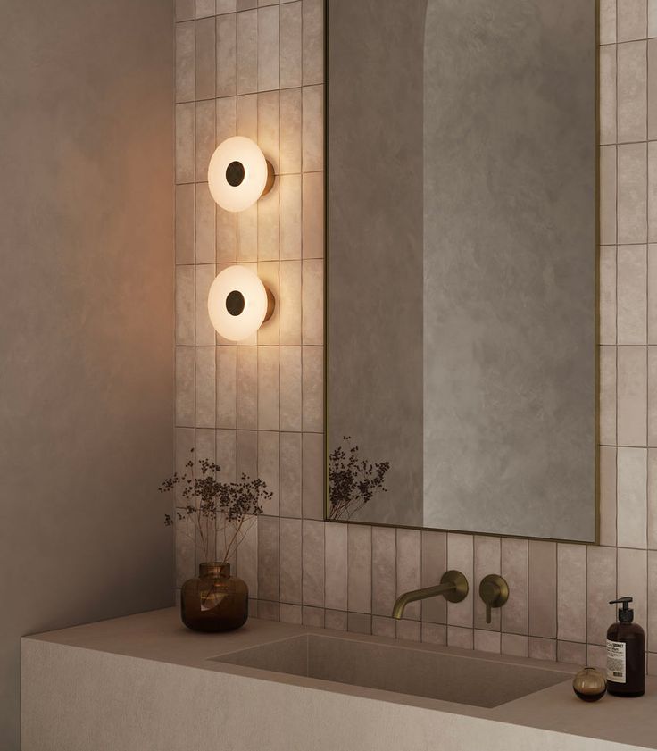 a bathroom sink with two lights on the wall above it and a mirror in front of it