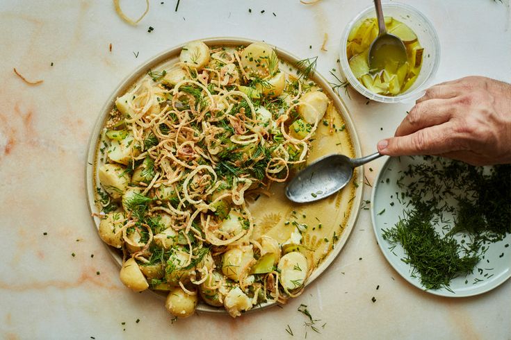 a plate with pasta and vegetables on it next to two bowls of olive oil, herbs and seasonings