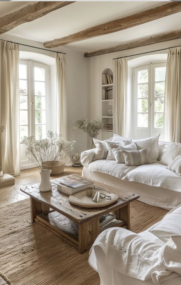 a living room filled with lots of white furniture and pillows on top of couches