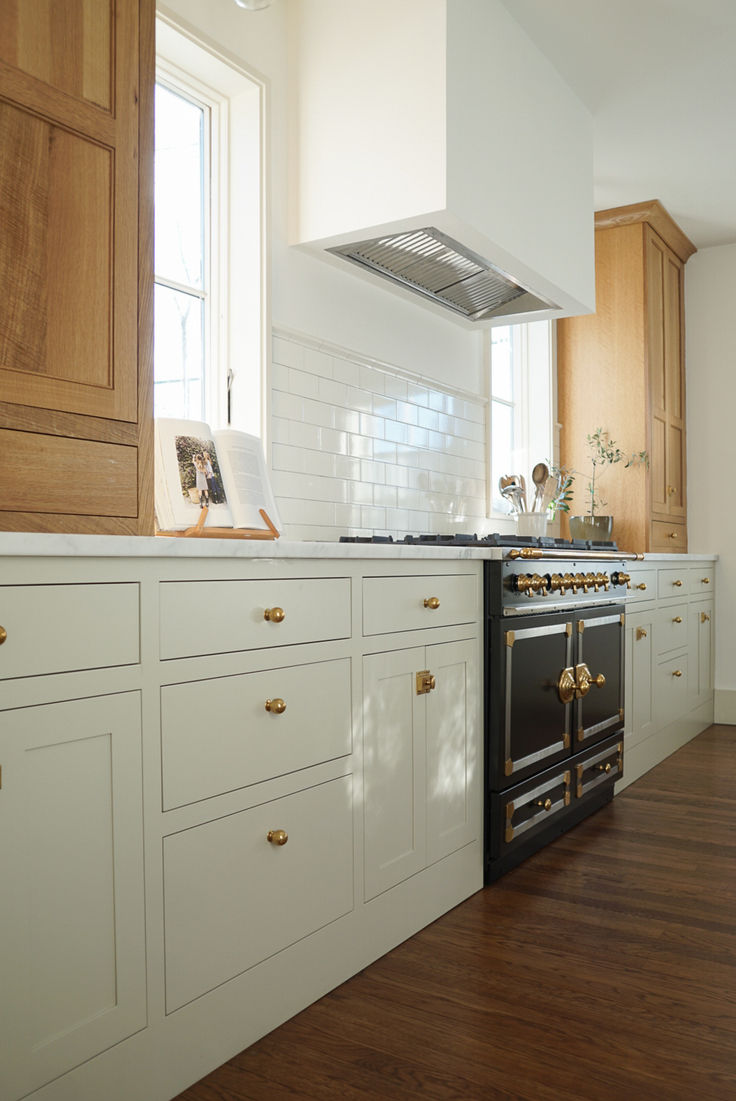 a kitchen with white cabinets and an oven in the center, along with wooden floors